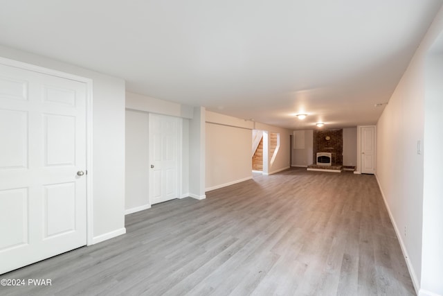 basement with light hardwood / wood-style flooring and a brick fireplace