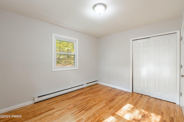 unfurnished bedroom featuring hardwood / wood-style flooring, a closet, and a baseboard radiator