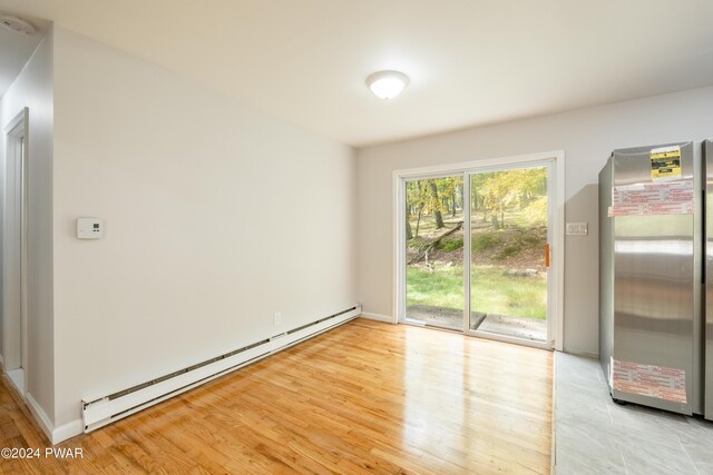 unfurnished dining area featuring light hardwood / wood-style floors and a baseboard heating unit