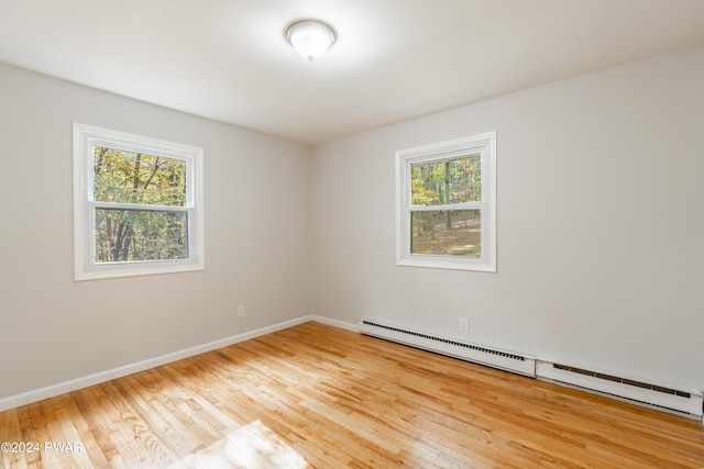 spare room featuring light wood-type flooring, a wealth of natural light, and a baseboard heating unit