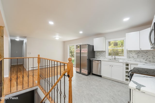 kitchen featuring white cabinets, sink, baseboard heating, and appliances with stainless steel finishes