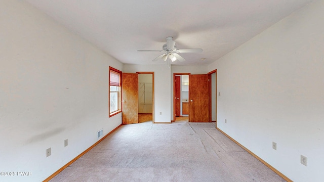 unfurnished bedroom featuring ceiling fan, light colored carpet, visible vents, baseboards, and a spacious closet