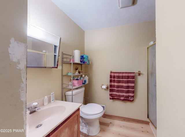 bathroom featuring vanity, toilet, wood-type flooring, and a shower with shower door