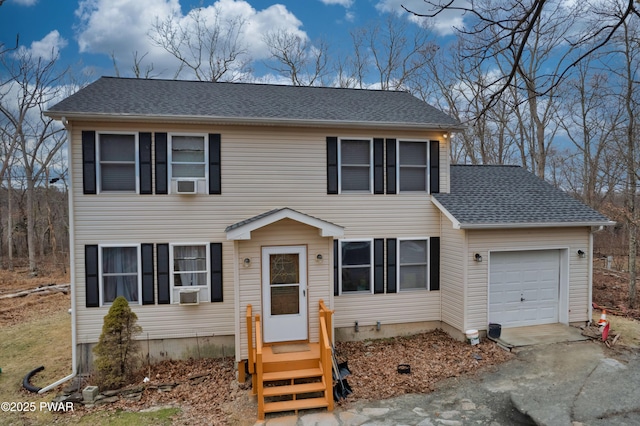 colonial-style house with a shingled roof, driveway, and an attached garage