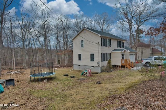 back of property featuring a lawn and a trampoline