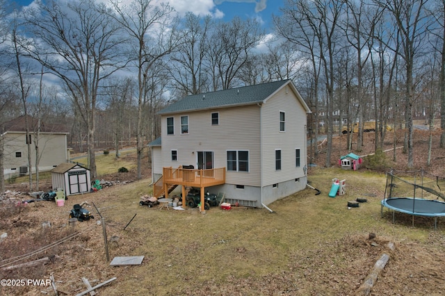 back of property with a lawn, a storage unit, a deck, and a trampoline