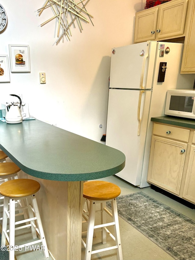 106 Keystone Ct, Dingmans Ferry, PA 18328 - kitchen featuring white appliances, light brown cabinets, a kitchen bar, a kitchen island, and dark countertops
