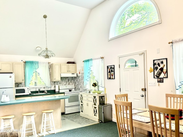 106 Keystone Ct, Dingmans Ferry, PA 18328 - kitchen with white appliances, under cabinet range hood, a breakfast bar area, high vaulted ceiling, and tasteful backsplash