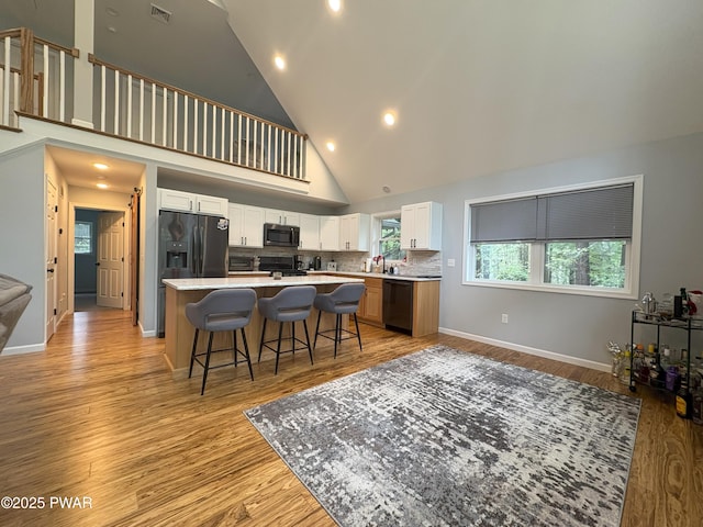 1006 Redlawn Ln, Lake Ariel, PA 18436 - kitchen featuring high vaulted ceiling, a kitchen breakfast bar, a center island, white cabinetry, and fridge with ice dispenser