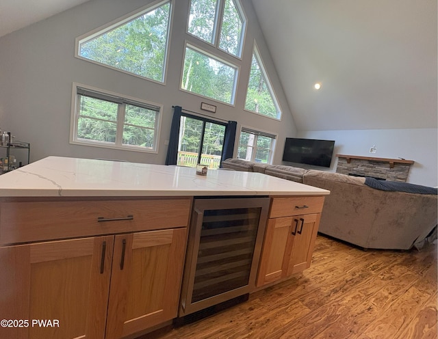 1006 Redlawn Ln, Lake Ariel, PA 18436 - kitchen featuring wine cooler, light wood-style floors, light stone countertops, high vaulted ceiling, and open floor plan