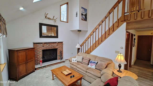 living area featuring a brick fireplace, stairway, wood finished floors, and high vaulted ceiling