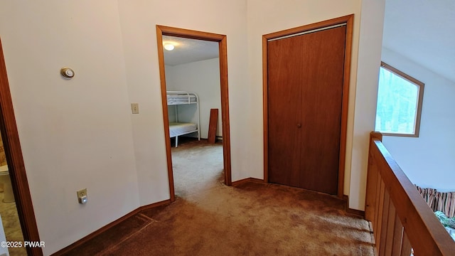 hall featuring baseboards and dark carpet