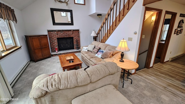 living room with light wood-style flooring, a brick fireplace, a baseboard heating unit, and vaulted ceiling