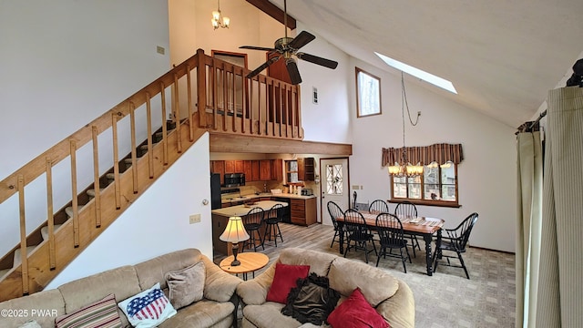 living room featuring light carpet, high vaulted ceiling, ceiling fan with notable chandelier, stairway, and a skylight