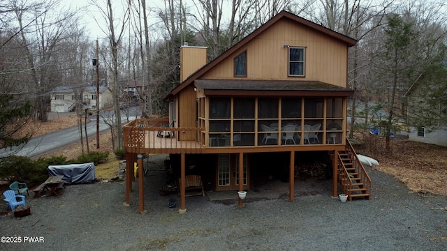 rear view of property with roof with shingles, a wooden deck, a sunroom, stairs, and a carport