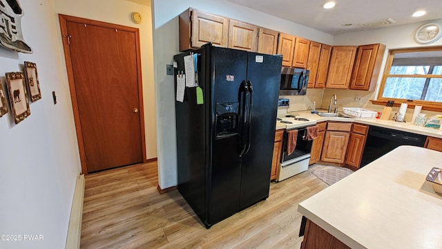 kitchen featuring light wood finished floors, black appliances, a sink, recessed lighting, and light countertops