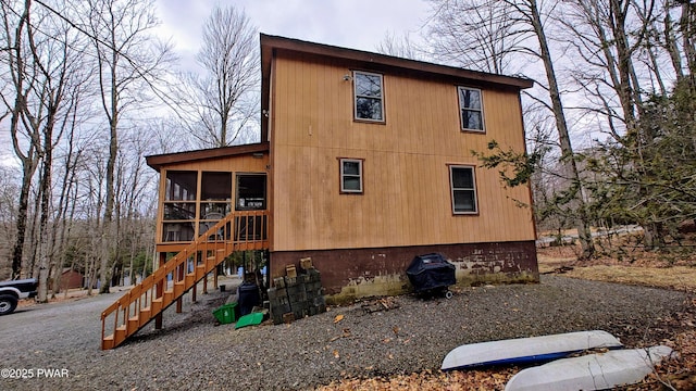 view of side of home with stairway and a sunroom