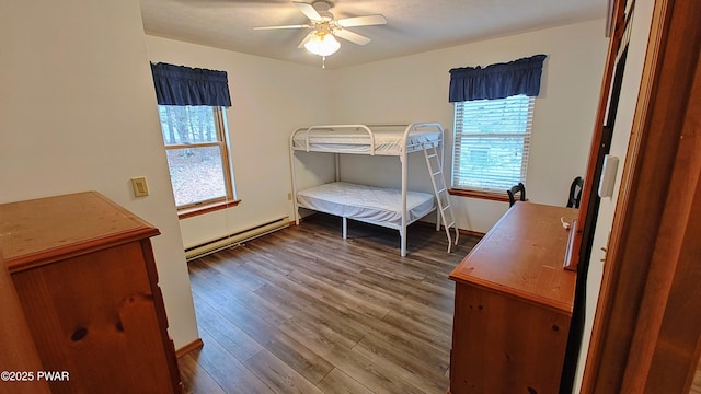 bedroom featuring baseboard heating, ceiling fan, and wood finished floors