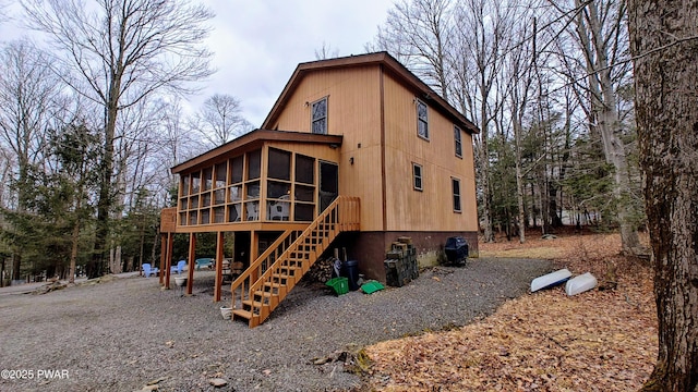 rear view of property featuring stairs and a sunroom