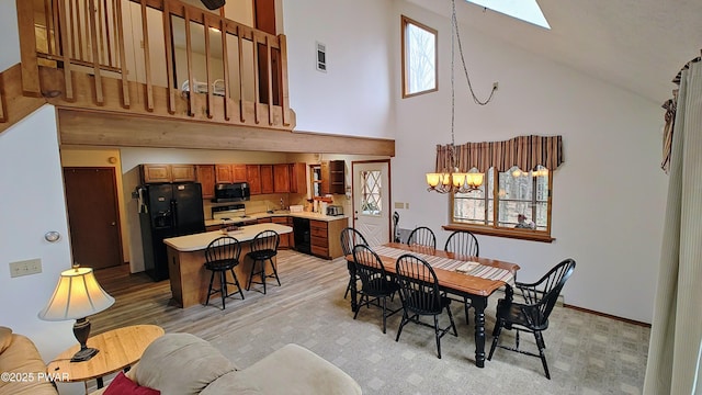 dining area featuring a skylight, visible vents, a chandelier, and high vaulted ceiling