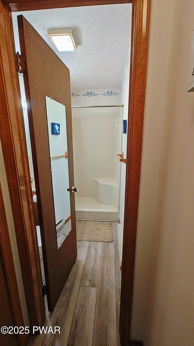 corridor with a textured ceiling and wood finished floors