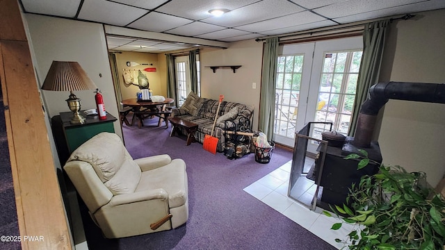 living room featuring a paneled ceiling and a wood stove