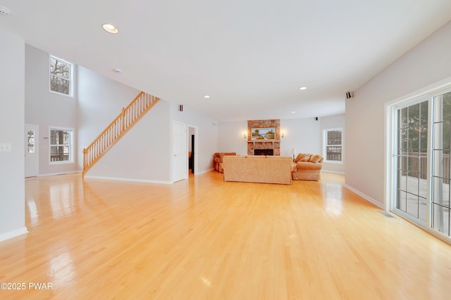 129 Lakewood Dr, Dingmans Ferry, PA 18328 - living area with healthy amount of natural light, a stone fireplace, stairs, light wood-style flooring, and recessed lighting
