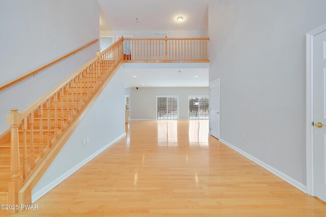 129 Lakewood Dr, Dingmans Ferry, PA 18328 - unfurnished living room with wood finished floors, stairway, and a high ceiling