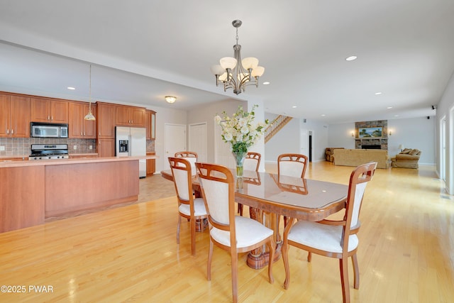 129 Lakewood Dr, Dingmans Ferry, PA 18328 - dining room featuring light wood-type flooring, a chandelier, recessed lighting, and a fireplace