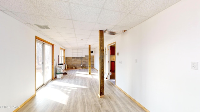 hallway with visible vents, a paneled ceiling, and light wood-type flooring