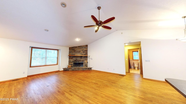 unfurnished living room with light wood-type flooring, visible vents, a fireplace, ceiling fan, and vaulted ceiling