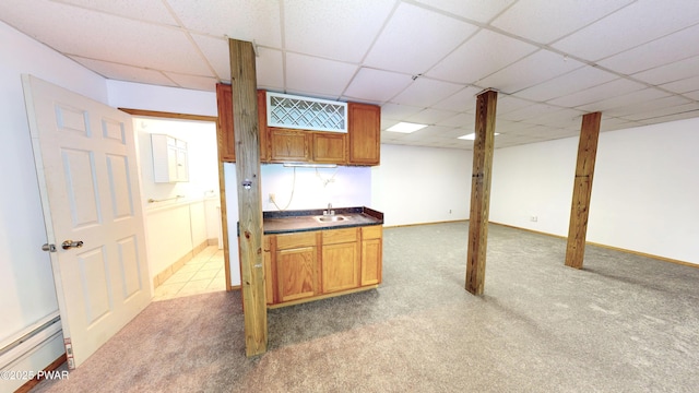 kitchen featuring a baseboard heating unit, dark countertops, carpet flooring, and a paneled ceiling