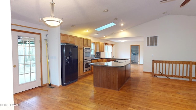 kitchen featuring dark countertops, visible vents, double oven, light wood-style floors, and black fridge with ice dispenser