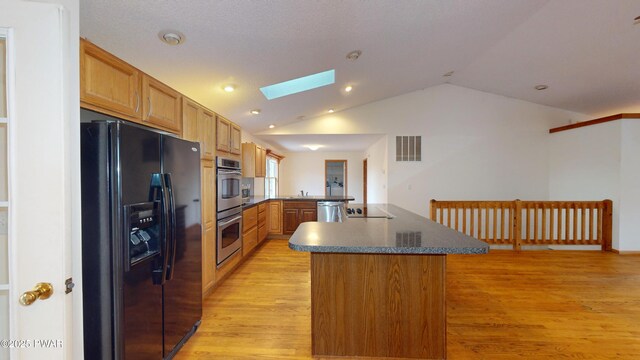 kitchen with visible vents, black appliances, light wood-style flooring, dark countertops, and a peninsula