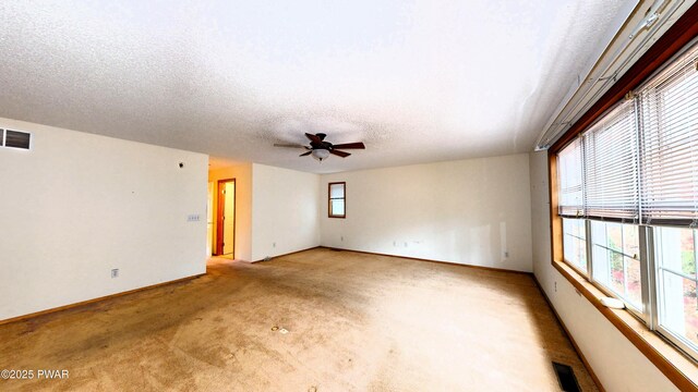 unfurnished room with visible vents, a healthy amount of sunlight, a textured ceiling, and carpet floors