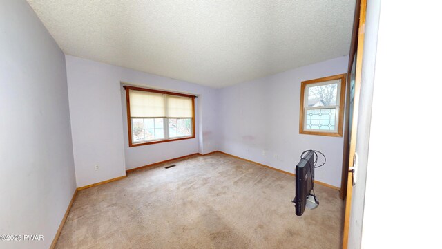 carpeted spare room featuring baseboards, visible vents, and a textured ceiling