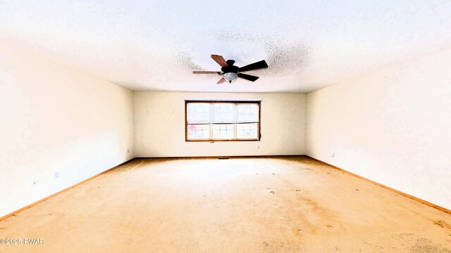 carpeted empty room with baseboards, a textured ceiling, and a ceiling fan