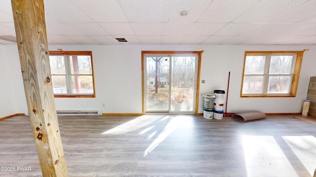 spare room with a paneled ceiling, visible vents, plenty of natural light, and wood finished floors