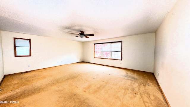 carpeted spare room featuring a ceiling fan, baseboards, and a textured ceiling