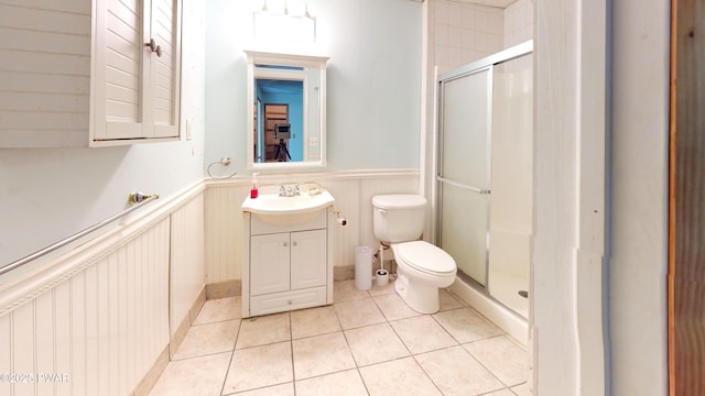 full bathroom with tile patterned flooring, a wainscoted wall, a shower stall, and toilet