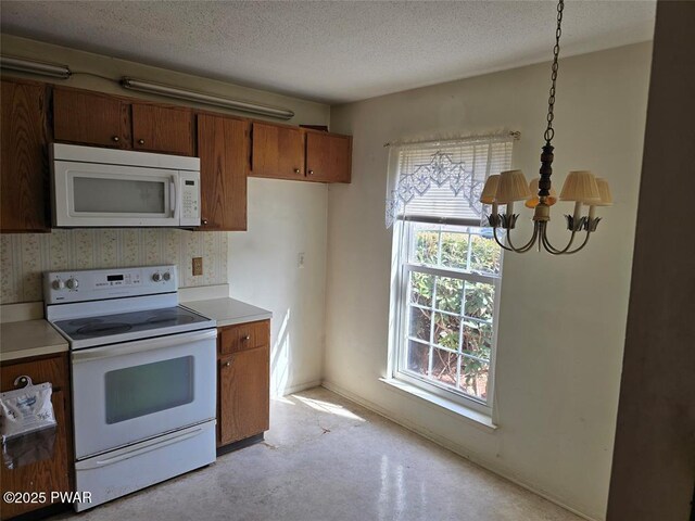 29 Burnett Way, Washingtonville, NY 10992 - kitchen with brown cabinetry, white appliances, an inviting chandelier, and plenty of natural light