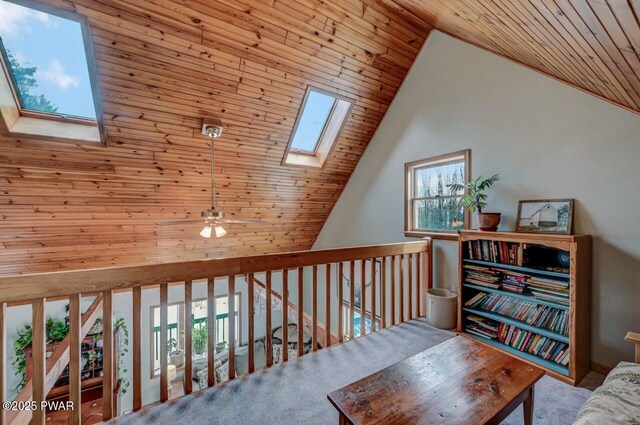 living area with a skylight, wood ceiling, lofted ceiling, and ceiling fan