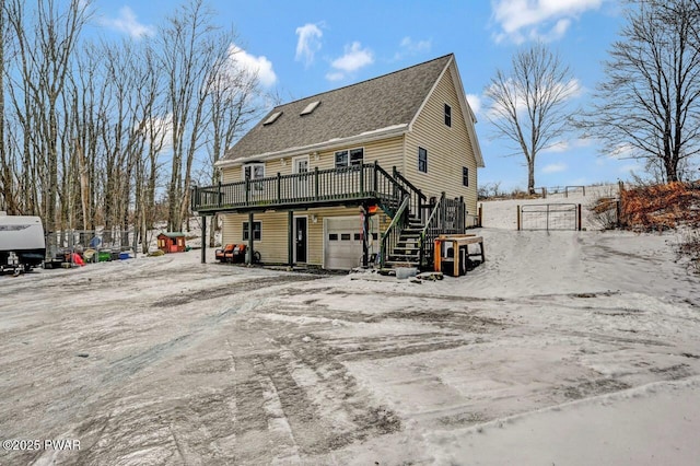 rear view of property with a deck, stairs, a shingled roof, a garage, and fence