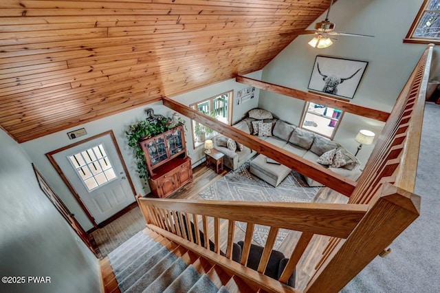 stairway featuring wood ceiling, healthy amount of natural light, a ceiling fan, and high vaulted ceiling
