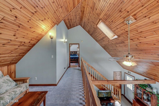 hall featuring lofted ceiling, a skylight, wooden ceiling, carpet, and an upstairs landing