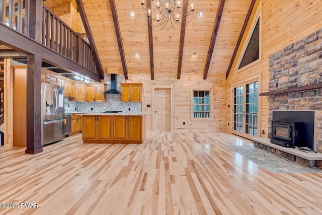 kitchen with wall chimney exhaust hood, wood ceiling, beam ceiling, high vaulted ceiling, and a wood stove