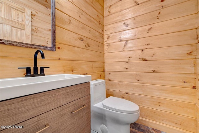 bathroom featuring wooden walls, vanity, and toilet