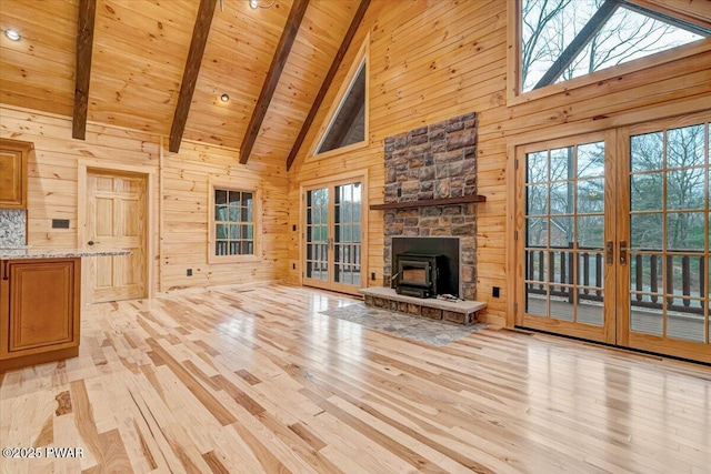 unfurnished living room with wood walls, a wood stove, high vaulted ceiling, beam ceiling, and wood ceiling