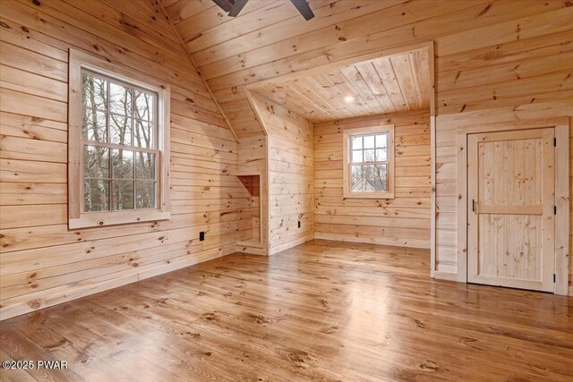 additional living space featuring wood walls, light wood-type flooring, wood ceiling, and vaulted ceiling