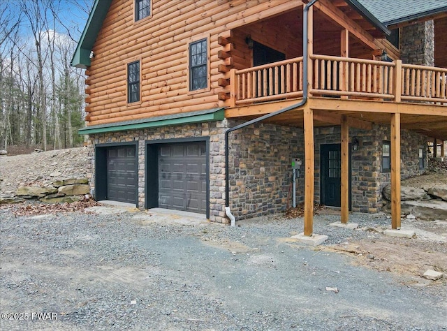 view of property exterior featuring a garage, a balcony, and a wooden deck